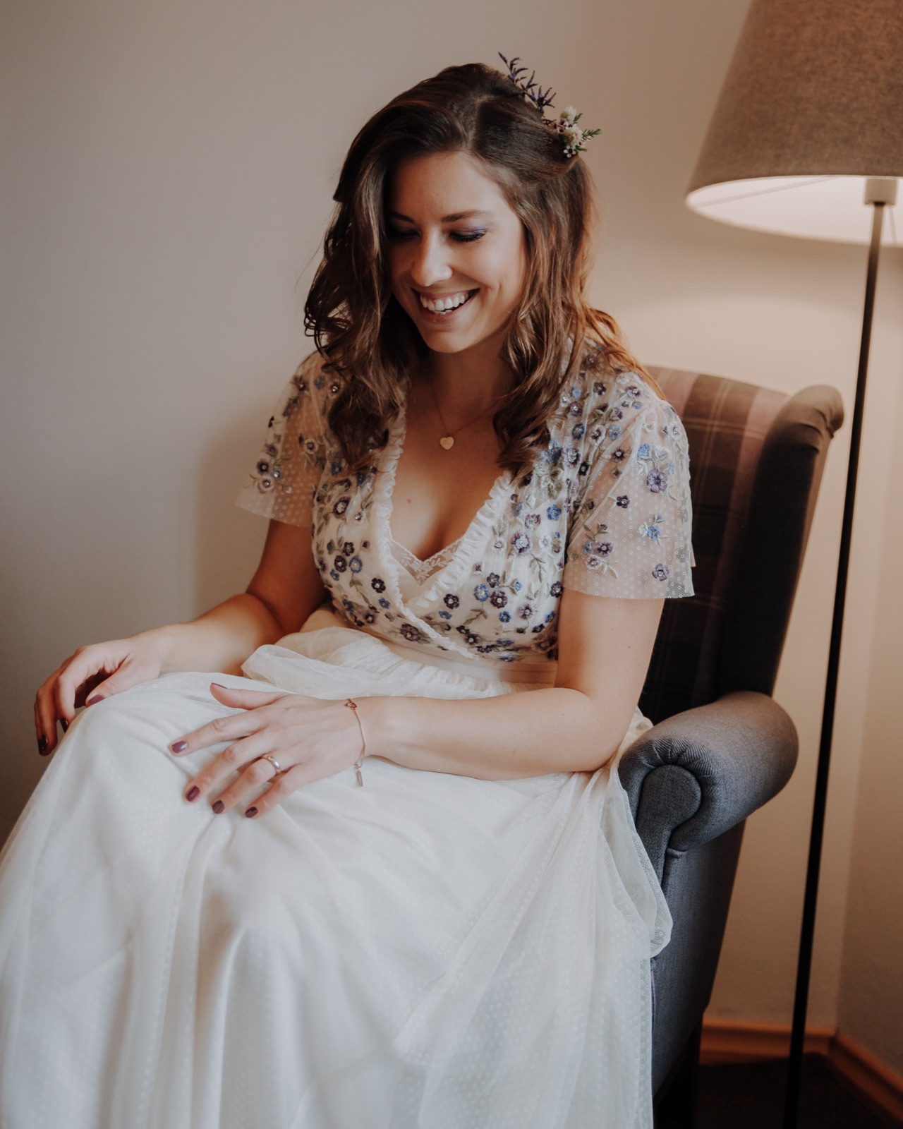 Braut lacht im weichen Fensterlicht während der Vorbereitung – Getting Ready Fotos zur Hochzeit.
