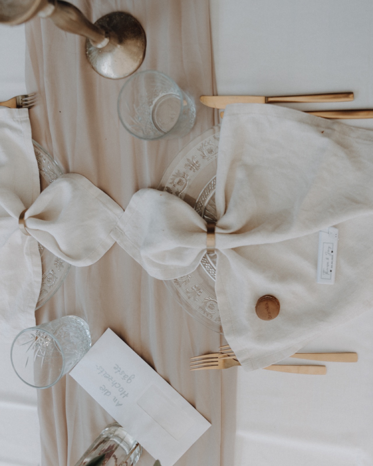Elegant gedeckter Hochzeitstisch am Abend mit Leinenservietten, Vintage-Gläsern und Gästekarte – auch solche Fotos gehören zur Hochzeitsfeier am Abend.