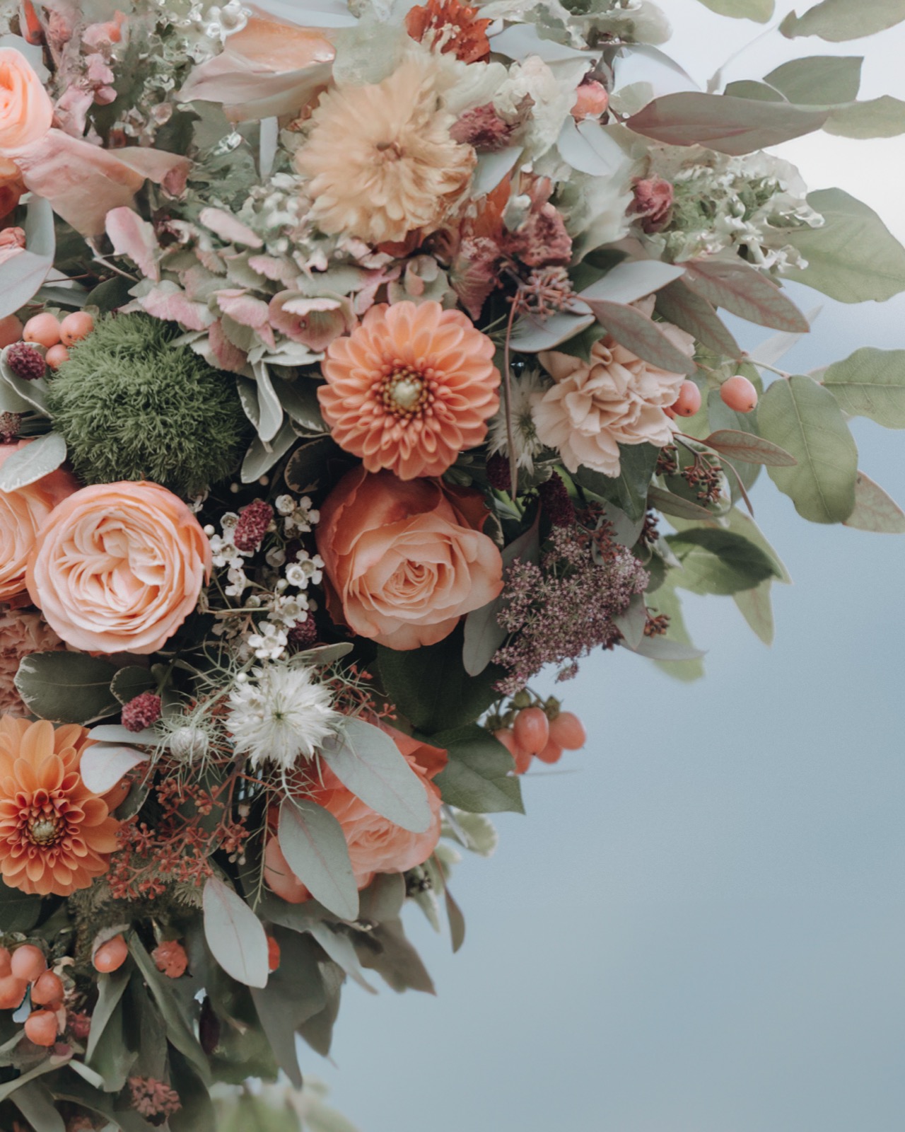 Nahaufnahme einer üppigen Blumendekoration in Pfirsich- und Roséfarben mit Rosen und Dahlien