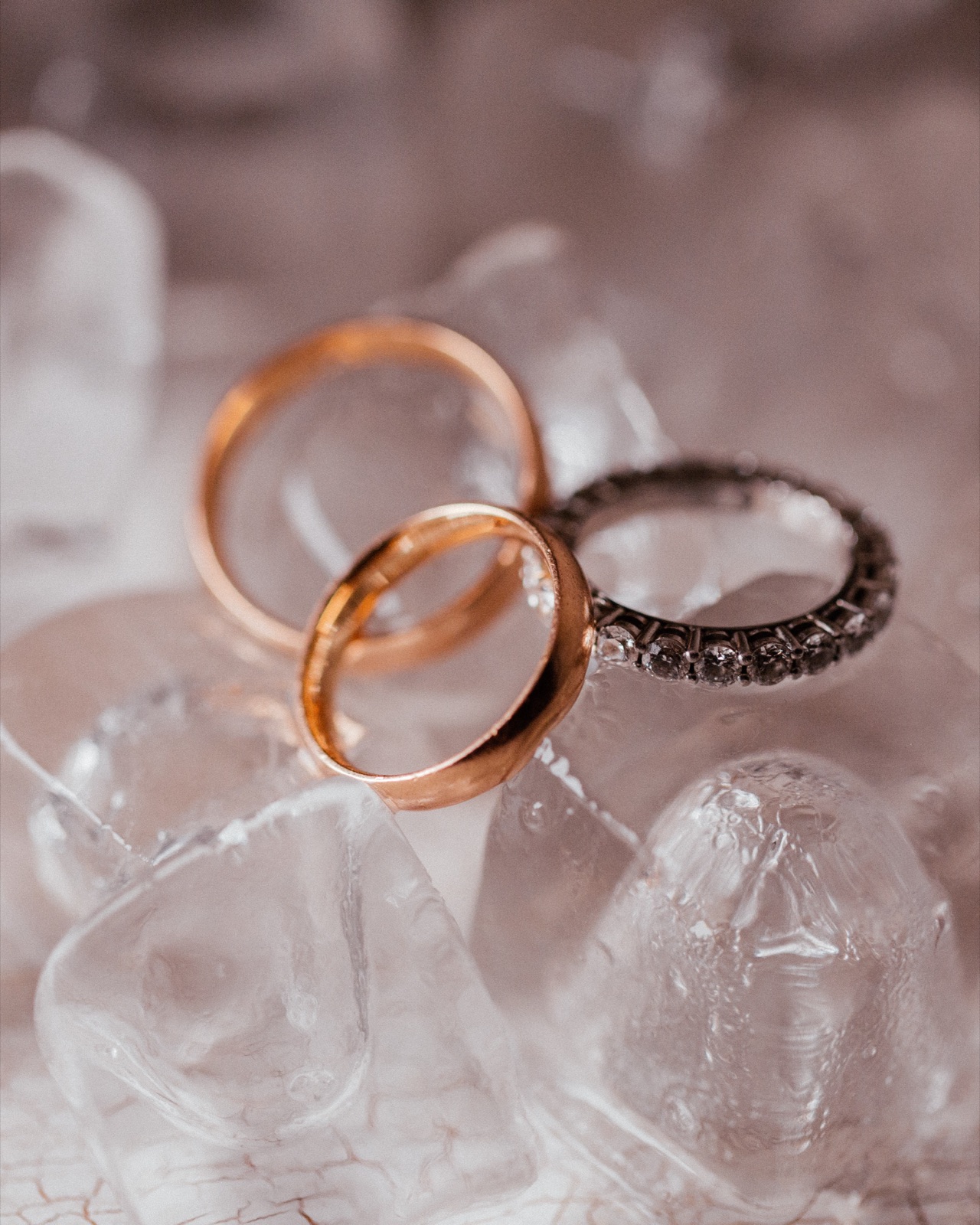 Nahaufnahme zweier Eheringe und eines Verlobungsrings auf Eiswürfeln, Detailaufnahme eines erfahrenen Hochzeitsfotografen