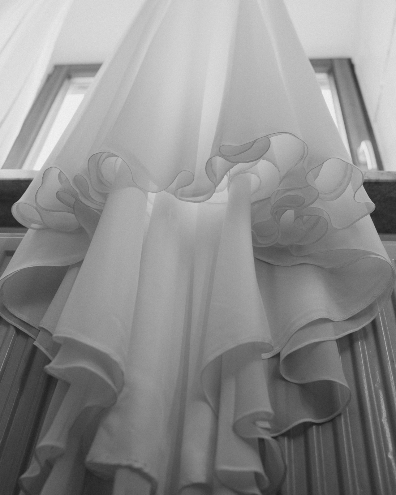 Detailaufnahme des Kleidsaums im Fensterlicht, Schwarz-Weiß – auch Details lassen sich zur Trauung ungestellt fotografieren.