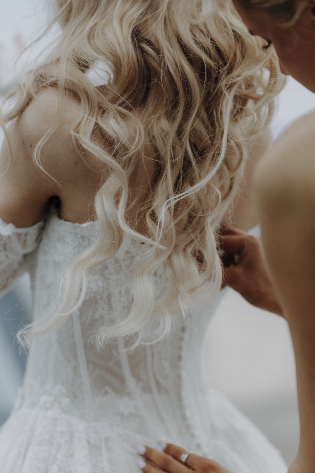 Rückenansicht von Herttas Brautkleid beim Zuknöpfen, Gesicht nicht sichtbar